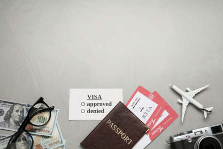 Flat lay composition with passport, toy plane and camera on gray background, space for text. Visa...