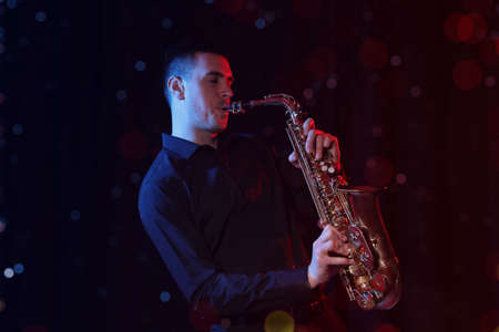Young man playing saxophone on dark background. bokeh effectの写真素材