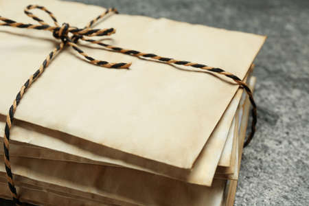 Stack of old letters tied with string on gray table, closeup