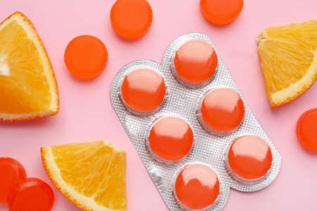 Many orange cough drops on pink background, flat layの写真素材