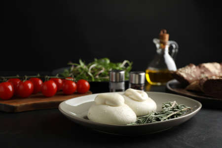 Delicious burrata cheese with rosemary on black table