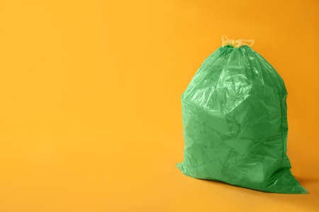 Trash bag full of garbage on yellow background. Space for text