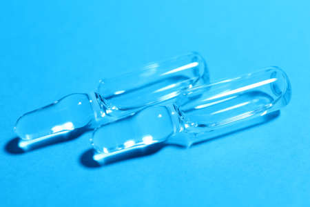 Pharmaceutical ampoules with medication on light blue background, closeup