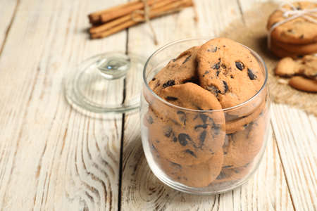 Jar of chocolate chip cookies on white wooden table. Space for text