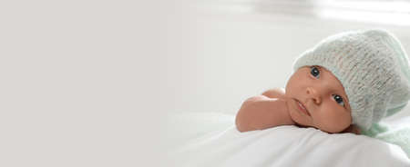 Adorable newborn baby in hat on bed indoors, space for text. banner designの写真素材