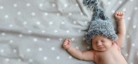 Cute newborn baby in warm hat sleeping on bed, top view with space for text. banner designの写真素材