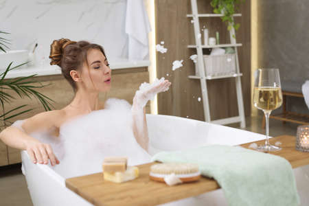 Beautiful woman enjoying bubble bath at home