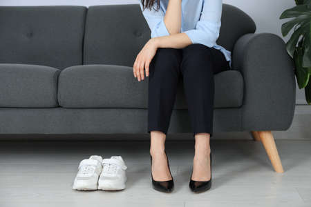 Comfortable sneakers near businesswoman wearing high heel shoes indoors, closeupの写真素材