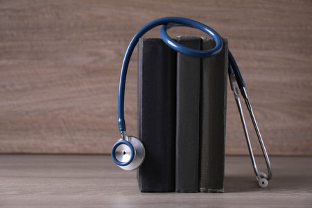 Student textbooks and stethoscope on wooden table. medical education