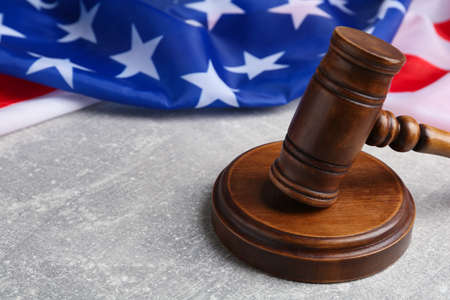 Judge's gavel and American flag on light gray table, closeup. Space for text