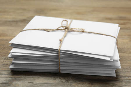 Stack of letters tied with twine on wooden table, closeup