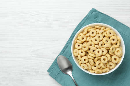 Bowl of sweet crispy corn rings on white wooden table, flat lay with space for text. breakfast cerealの写真素材