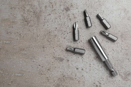 Different drill bits on gray table, flat lay. Space for text