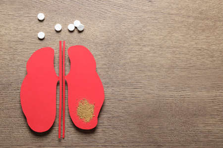 Paper cutout, sand and pills on wooden table, flat lay with space for text. Kidney stone diseaseの写真素材