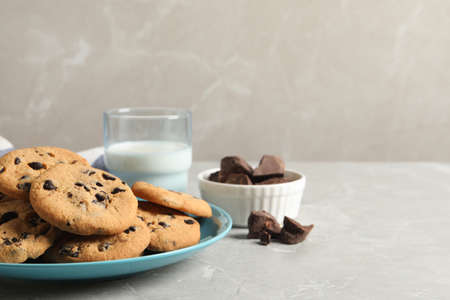 Plate with delicious chocolate chip cookies on gray marble table. Space for text