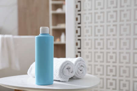 Bottle of shower gel and fresh towels on white table in bathroom. Space for text