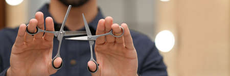 Hairstylist holding professional scissors in beauty salon, closeup. banner design