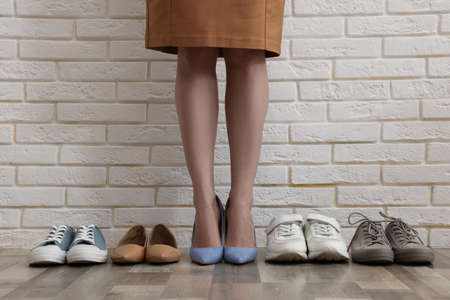 Different comfortable footwear near woman wearing high heeled shoes indoors, closeupの写真素材