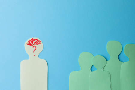 Paper cutout of crowd with one human silhouette different from others on light blue background, flat lay. Emotional managementの写真素材
