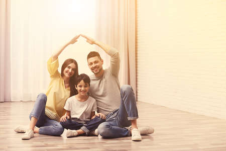 Happy family forming house roof with their hands at home. insurance conceptの写真素材