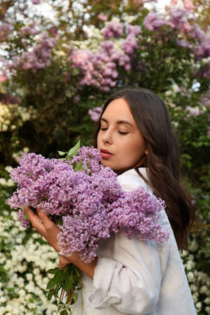 Attractive young woman with lilac flowers outdoors