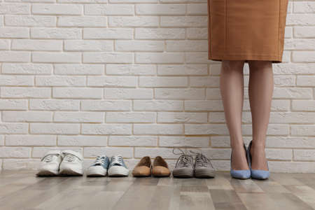 Different comfortable footwear near woman wearing high heeled shoes indoors, closeupの写真素材