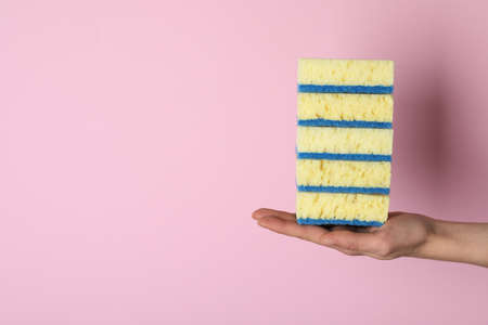 Woman holding sponges on pink background, closeup. Space for textの写真素材