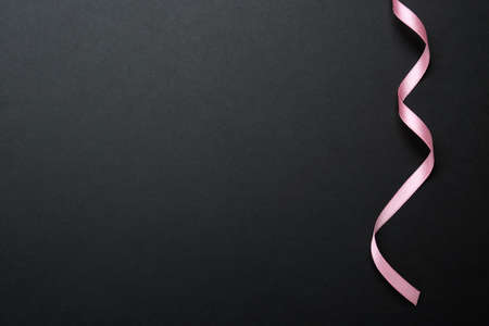 Beautiful pink ribbon on black background, top view. Space for textの写真素材