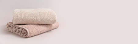 Two folded beige towels on light background, space for text. banner designの写真素材