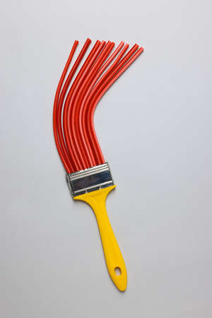 Brush with red straws on light gray background, top view. creative concept