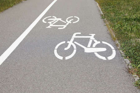 Bicycle lane with white sign painted on asphalt near sidewalk