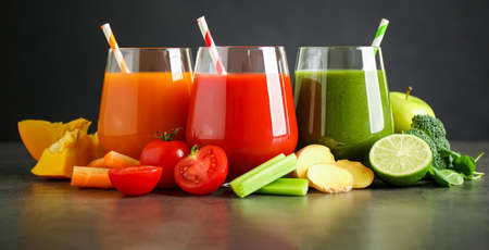 Different tasty juices and fresh ingredients on gray table against black background. banner designの写真素材