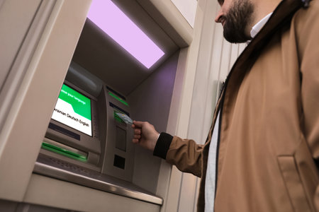 Man inserting credit card into cash machine outdoors, low angle viewの写真素材