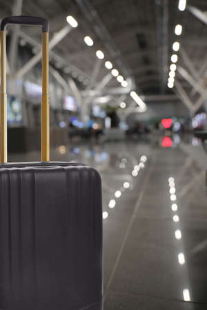 Stylish black suitcase in waiting area at airport terminal