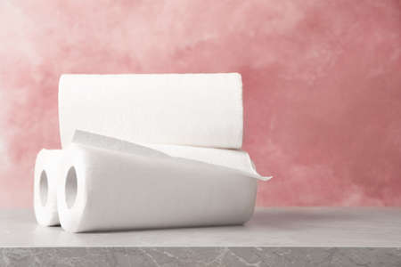 Rolls of white paper towels on gray table near pink wall. Space for textの写真素材