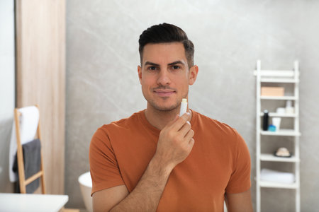 Man applying hygienic lip balm in bathroomの写真素材