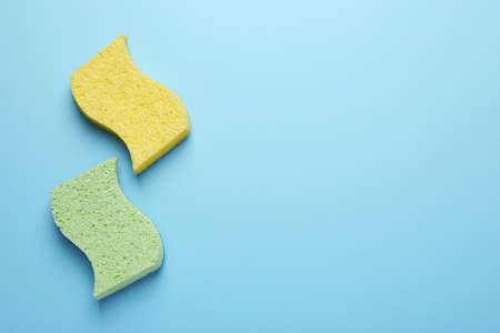 New sponges on light blue background, flat lay. Space for text