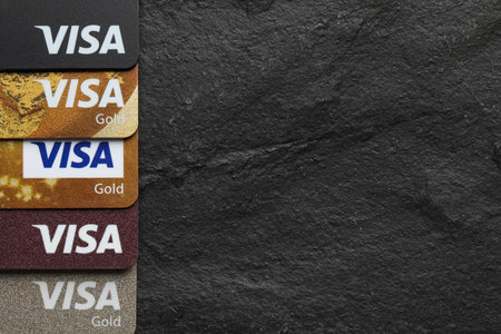 MYKOLAIV, UKRAINE - FEBRUARY 22, 2022: Visa credit cards on black background, flat lay. Space for...