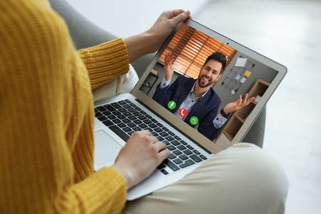 Woman talking with handsome man using video chat on laptop indoors, closeup. Online dating