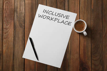 Inclusive workplace. Paper, pen and cup of coffee on wooden table, flat lay