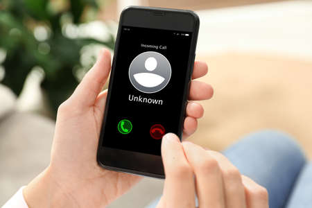 Woman declining incoming call from unknown caller indoors, closeup. Be careful - fraudの写真素材