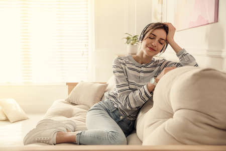 Young woman listening to music on sofa at home