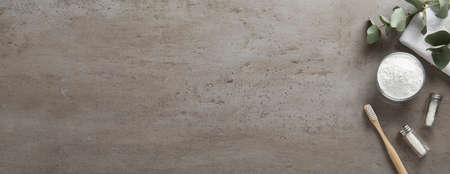 Flat lay composition with tooth powder and eucalyptus on gray table, space for text. banner design