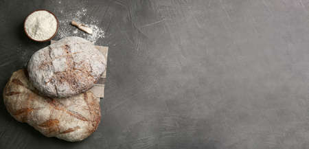 Tasty freshly baked bread on gray table, flat lay with space for text. banner design