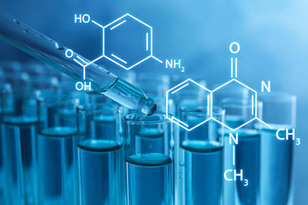 Dripping reagent into test tube with liquid on blue background, closeup