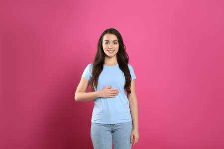 Happy healthy woman touching her belly on pink backgroundの写真素材