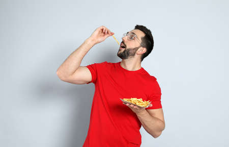 Man eating french fries on gray backgroundの写真素材
