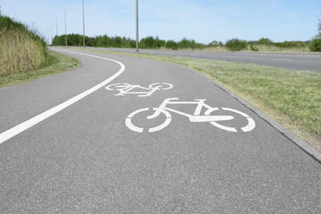Bicycle lane with white sign painted on asphalt near sidewalk