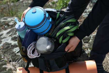 Hiker packing backpack on rocky hill, closeup