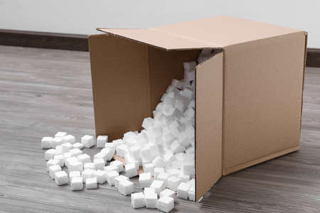 Overturned cardboard box with cubes on wooden floor indoors